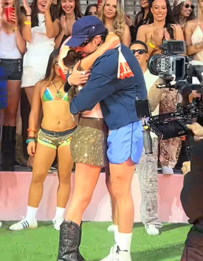 Bad Bunny hugging a woman on stage, surrounded by fans, after a steamy dance move. Bad Bunny hugging a woman on stage, surrounded by fans, after a steamy dance move.