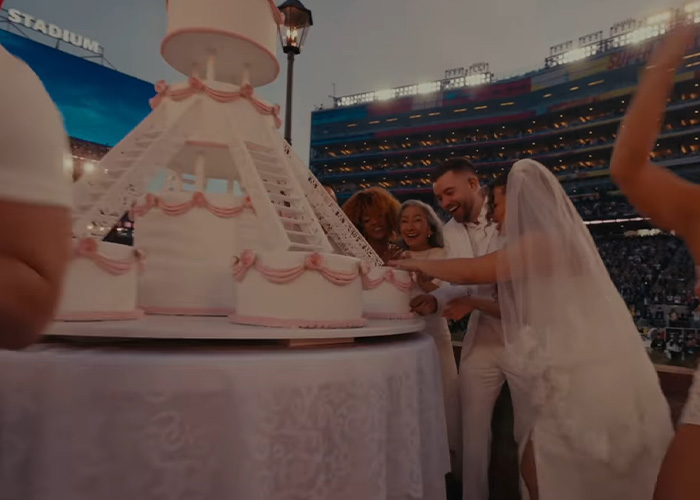 Bad Bunny and wedding guests gather around a large wedding cake, a scene from his steamy dance move performance. Bad Bunny and wedding guests gather around a large wedding cake, a scene from his steamy dance move performance.