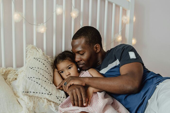 A dad hugging his daughter in bed. Having daughters can change dads' view and understanding of women.