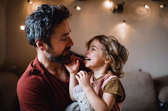 A dad holding his laughing daughter. Dads with daughters often find their understanding of women changes.