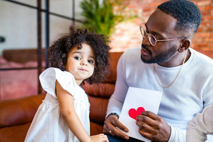 A dad and his daughter looking at a card with two hearts. The dad's view and understanding of women changed.