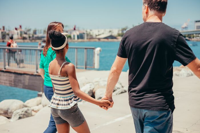 A dad holding his daughter's hand while walking. Dads with daughters often gain a new understanding of women.