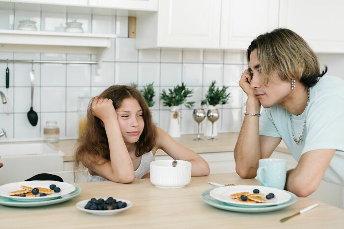 A dad and his daughter sitting at a kitchen table with breakfast. Dads with daughters often have a changed view of women.