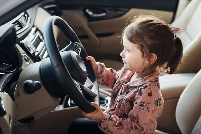 Little girl pretending to drive a car, representing the evolving view and understanding of women.