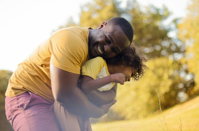A dad hugging his laughing daughter in a field. Dads' understanding of women changed.