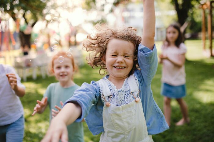 Happy daughters playing outdoors with bubbles. Dads' understanding of women changed.
