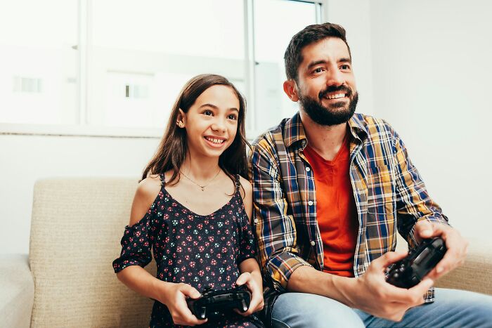 A dad and his daughter playing video games. Dads' understanding of women changed.