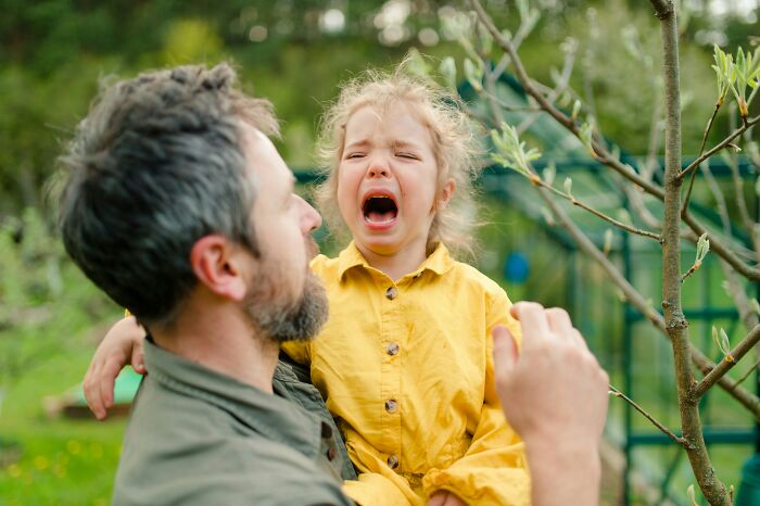 A dad holding his crying daughter. Dads' understanding of women changed.