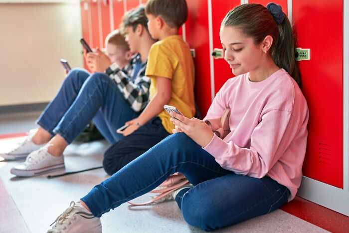 Teenage girl using a phone at school, reflecting modern views and understanding of women.