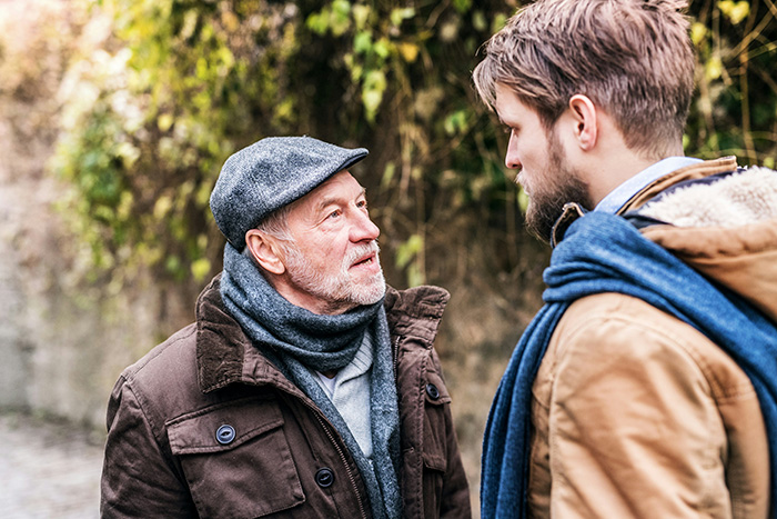 A man financially supporting his son in his 40s, talking with his son outdoors. A man financially supporting his son in his 40s, talking with his son outdoors.