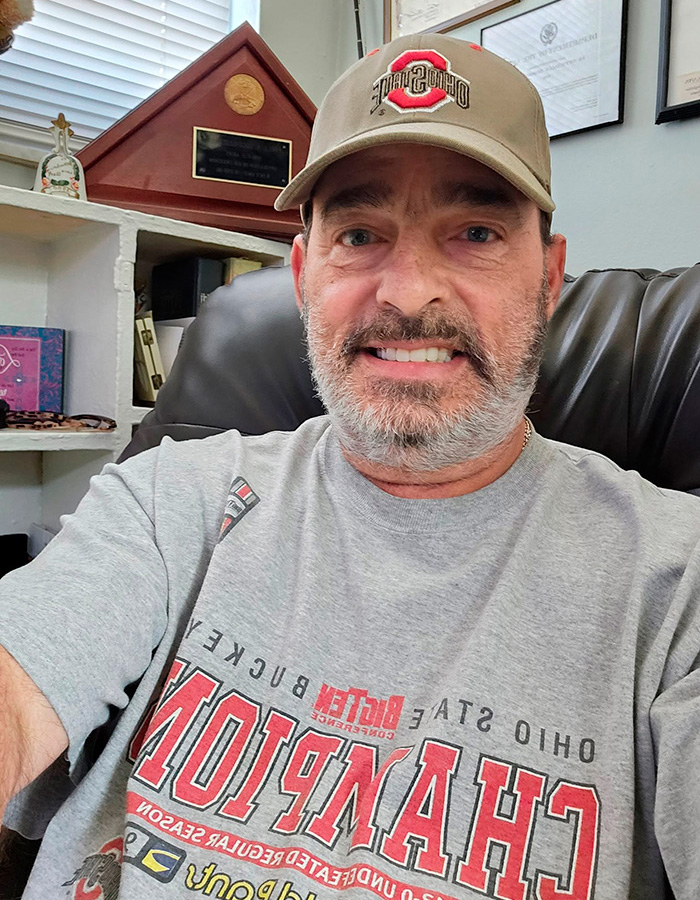 A smiling Army veteran in a grey t-shirt and baseball cap, related to a Walmart parking lot dispute. A smiling Army veteran in a grey t-shirt and baseball cap, related to a Walmart parking lot dispute.