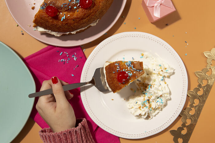 A slice of cake with whipped cream and sprinkles on a plate, symbolizing sweet industries that make millions.