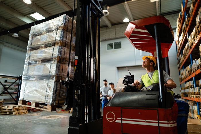Forklift operator moving large boxes in a warehouse, an unpopular industry that makes millions.