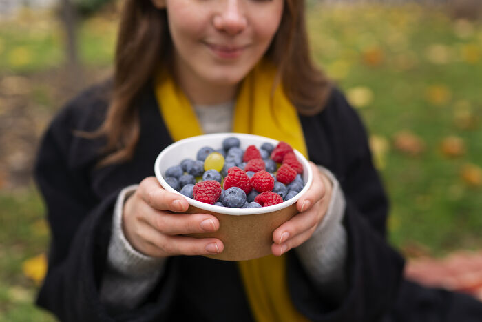 A person holding a bowl of fresh berries, illustrating an aspect of the food industry, making millions.