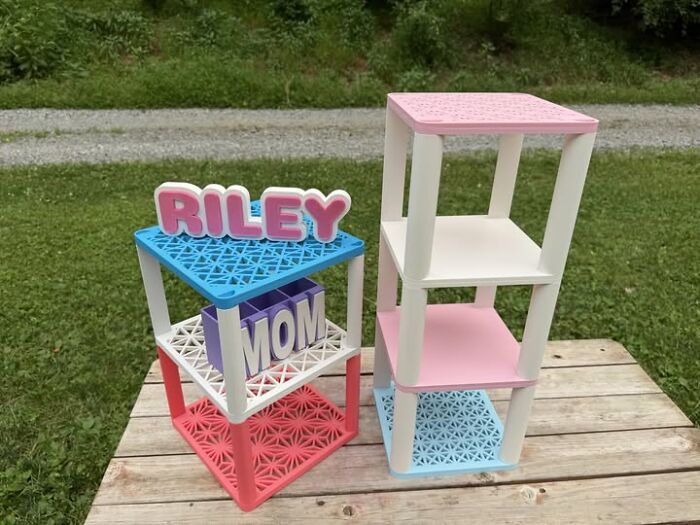 Two colorful, multi-tiered shelves created using a 3D printer, one with the name RILEY and MOM.