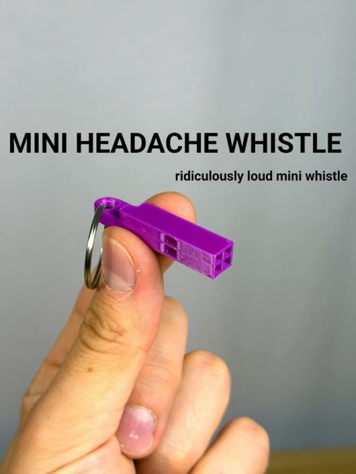 A hand holds a small purple 3D printer created mini headache whistle, loud despite its size.