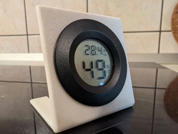 A white 3D printer stand holds a digital thermometer, showcasing cool things made with a 3D printer.