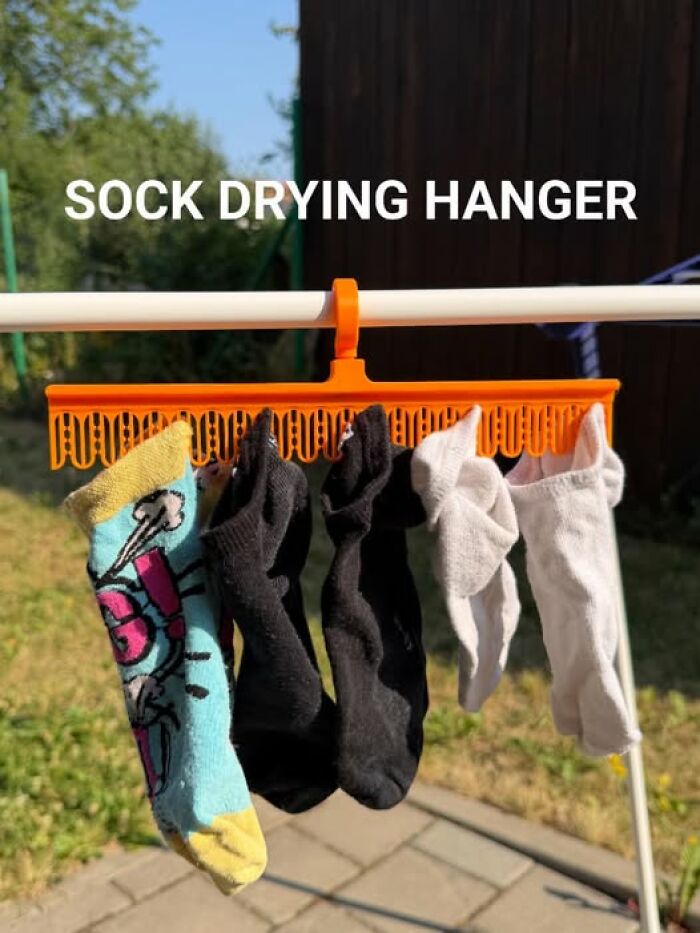 Socks hang on an orange 3D printer sock drying hanger, an example of functional 3D printed objects.