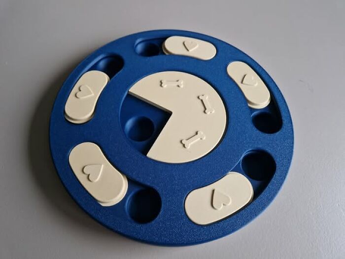 A blue and beige dog puzzle, a cool and functional thing created with a 3D printer, on a gray surface.