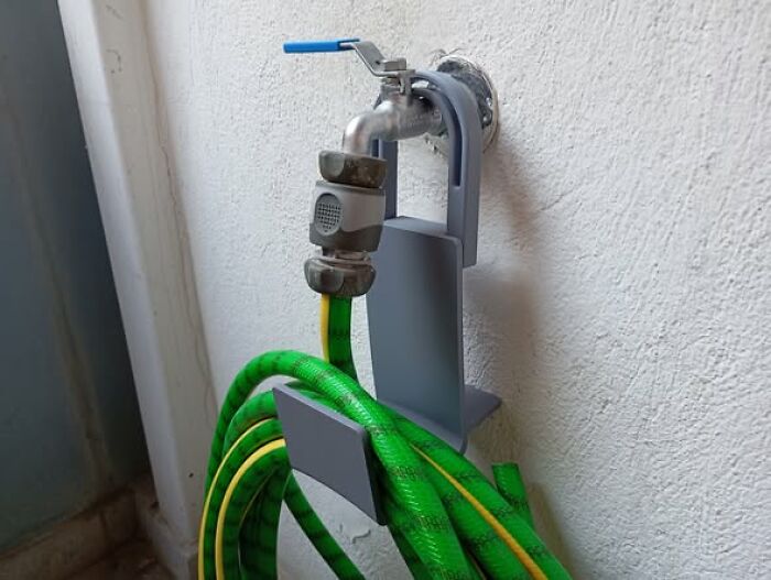 A 3D printer created hose holder attached to an outdoor faucet, showcasing a functional item for organization.
