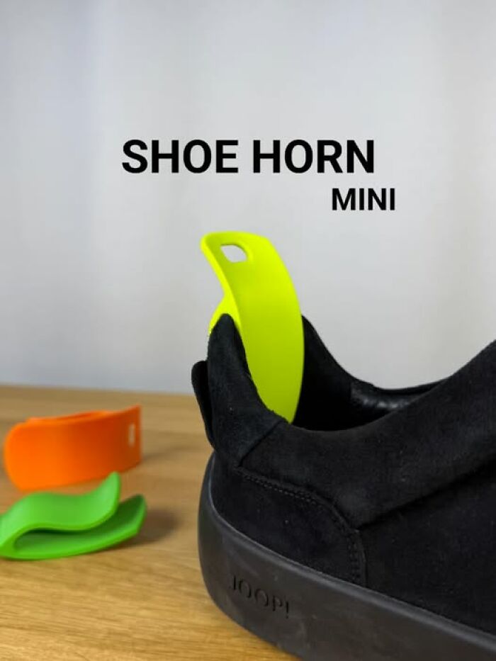 A neon yellow mini shoe horn, a functional thing created with a 3D printer, helps put on a black shoe.
