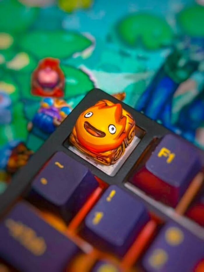 A close-up of a keyboard with a cheerful flame character keycap, a cool thing created using a 3D printer.