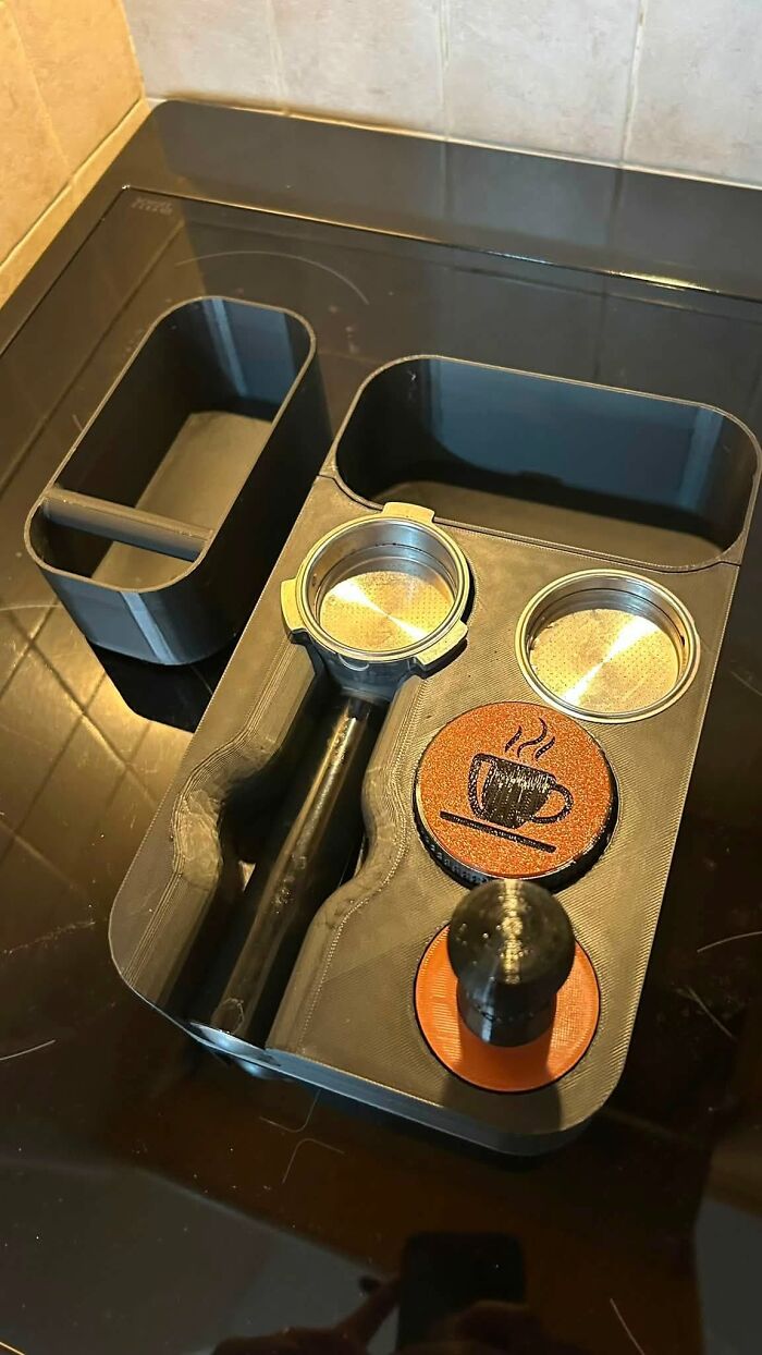 A 3D printer created coffee station organizer, holding a portafilter, tamper, and two filter baskets.