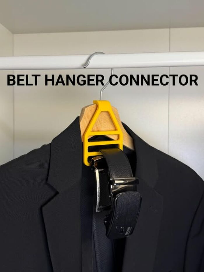 A black suit jacket with a yellow 3D printed belt hanger connector holding a belt on a clothes rail, showing functional 3D printer creations.