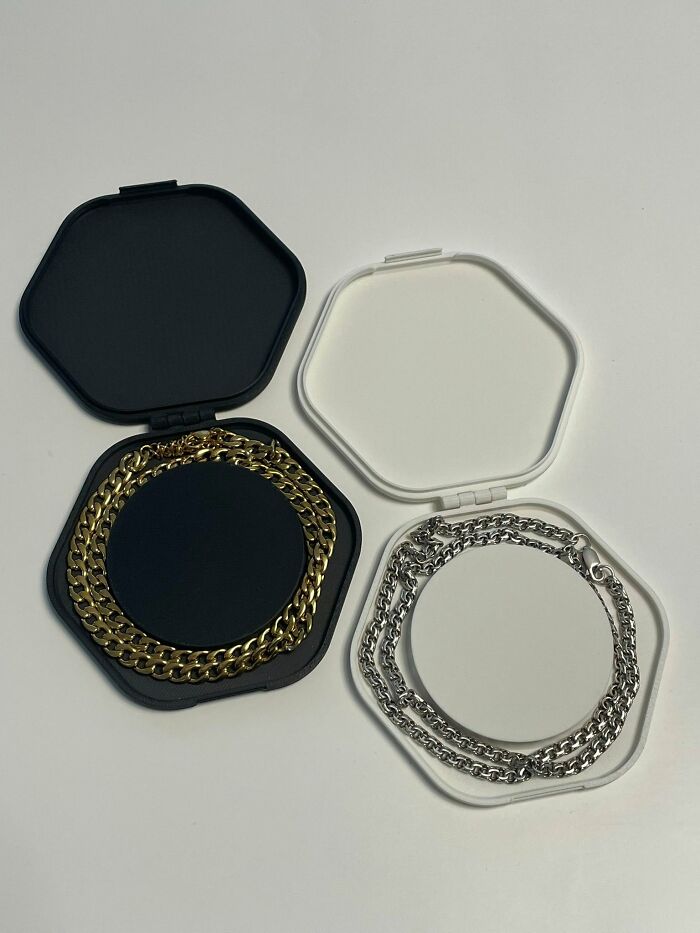 Two 3D printed hexagonal cases, one black with a gold chain and one white with a silver chain, for cool 3D printer storage.