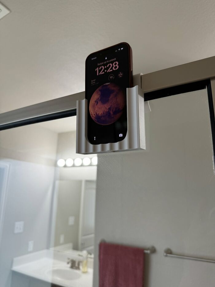 A smartphone securely held in a white 3D printed shower caddy, highlighting cool 3D printer designs for convenience.