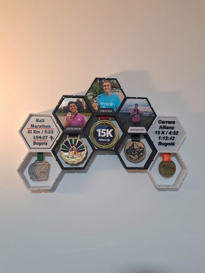 A wall-mounted display, 3D printed, showcasing running medals and photos in a hexagonal pattern.