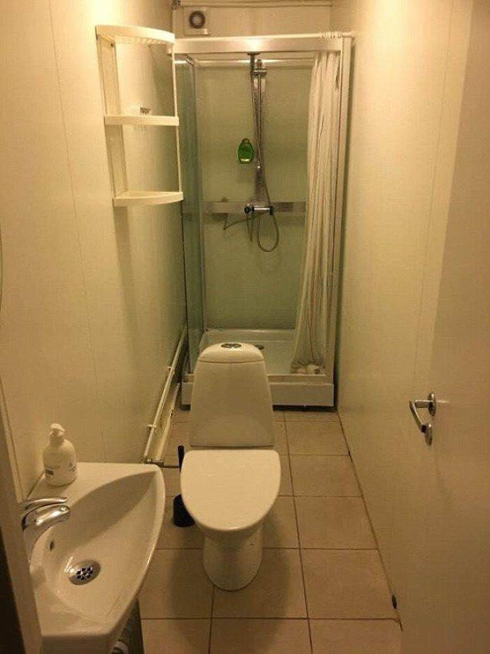 A tiny bathroom with a toilet, sink, and shower. The space is cramped, creating a terribly designed bathroom.