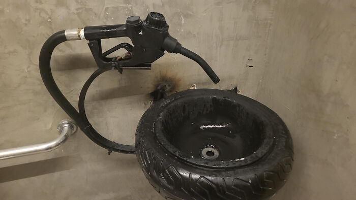 Sink made from a tire with a gas pump nozzle as a faucet, an example of terribly designed bathrooms.