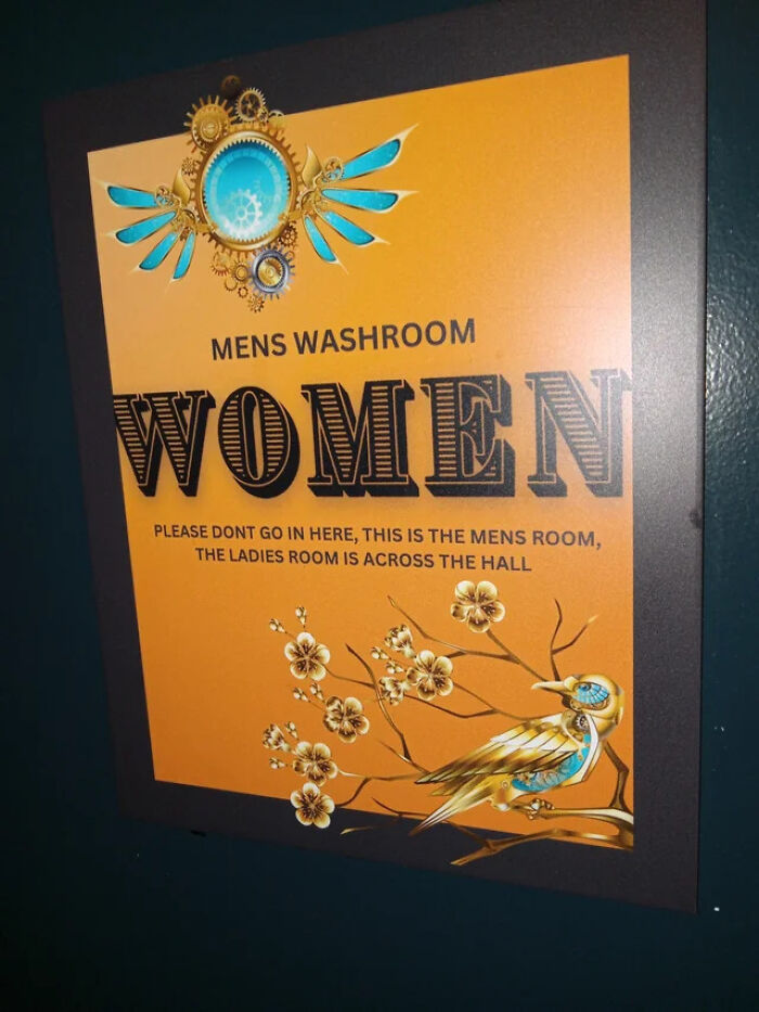 A confusing washroom sign for terribly designed bathrooms, indicating MEN'S WASHROOM with the word WOMEN prominently displayed.