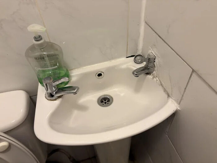 Corner sink with two mismatched faucets and a soap dispenser, showcasing terribly designed bathrooms.