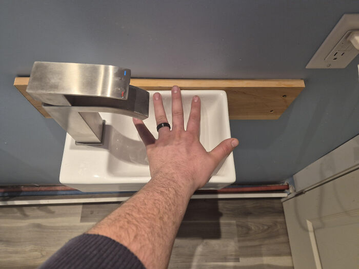A terribly designed bathroom sink with a faucet extending past the basin, making it difficult to wash hands.