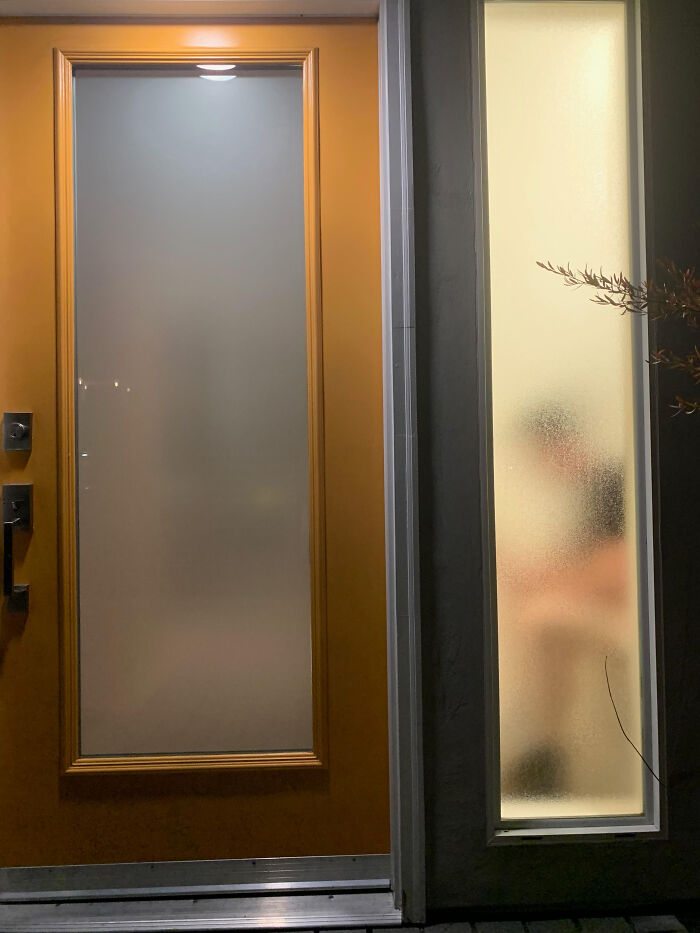 A poorly designed bathroom with a translucent window showing a person taking a shower, visible from outside.