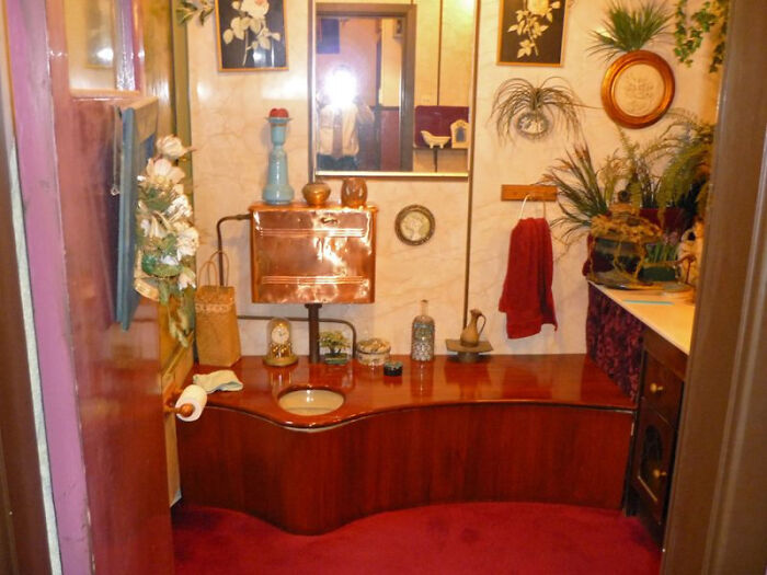 Terribly designed bathroom featuring an unusual wooden toilet and copper tank, showcasing unique bathroom design elements.