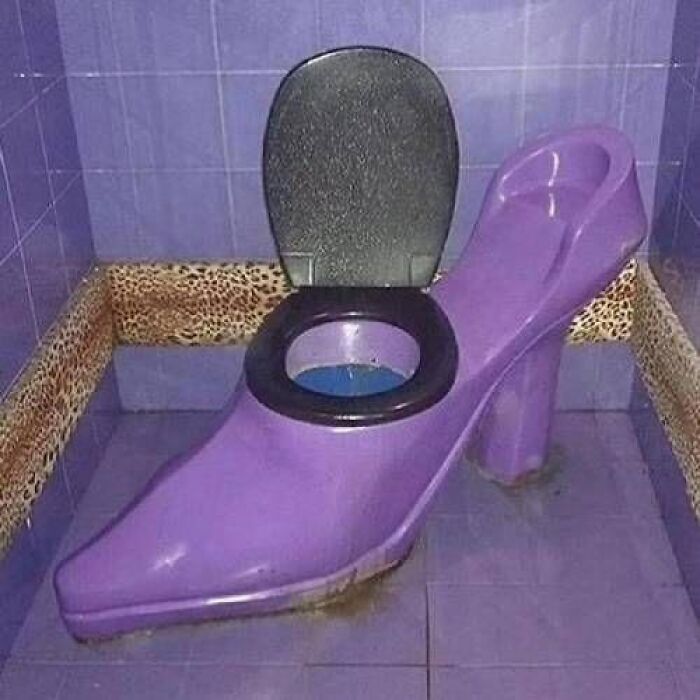 Terribly designed bathroom with a purple high-heel shaped toilet, adding an unusual touch to bathroom designs.