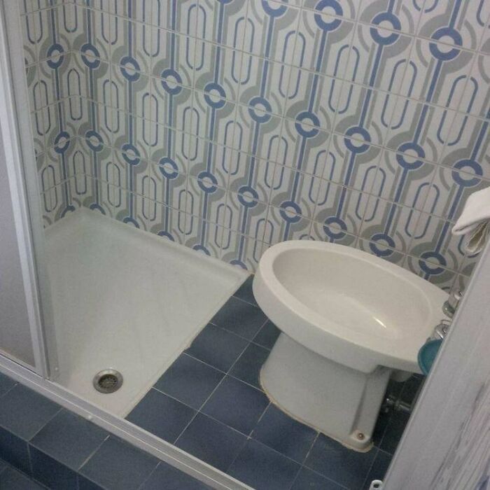 Terribly designed bathroom with a bidet placed right next to a shower, showcasing poor bathroom layout choices.