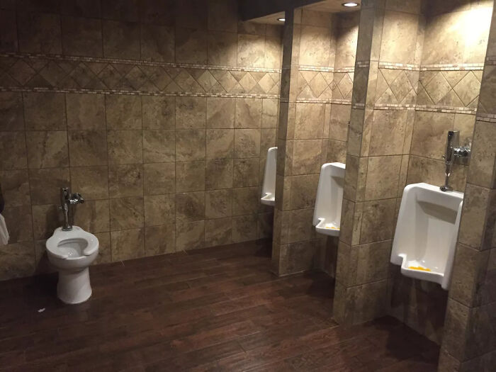 A spacious bathroom with multiple urinals and one low-set toilet, showcasing terribly designed bathrooms.