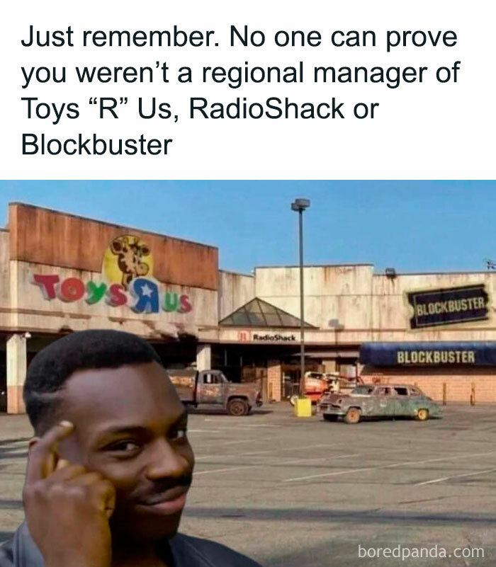 A man pointing to his temple with Toys R Us and Blockbuster in the background, a relatable ancient meme.