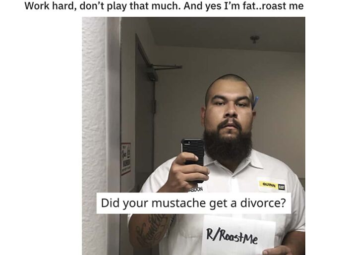 A man with a beard holds a sign that reads R/RoastMe with the clever clapback Did your mustache get a divorce?