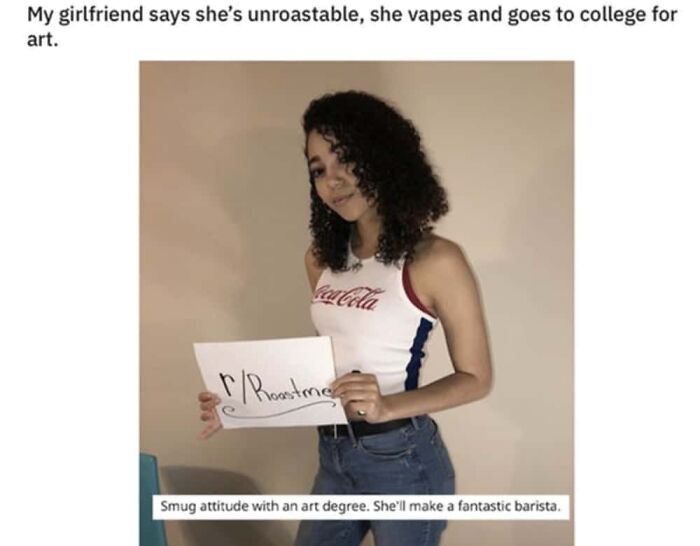A young woman in a Coca-Cola tank top holds a sign for R/RoastMe, featuring a clever clapback about her art degree.