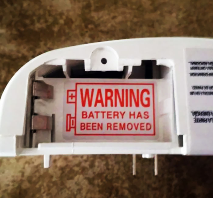 A hilariously failed sign warns Battery Has Been Removed on an empty battery compartment.