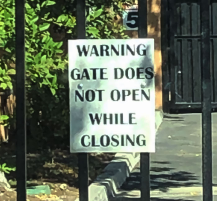 A warning sign on a gate that reads 'Gate does not open while closing', a hilarious sign failure.