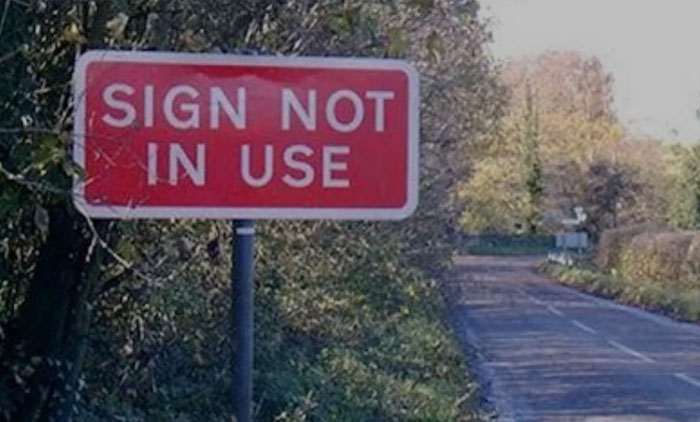 A hilariously failed sign that reads SIGN NOT IN USE on a roadside.