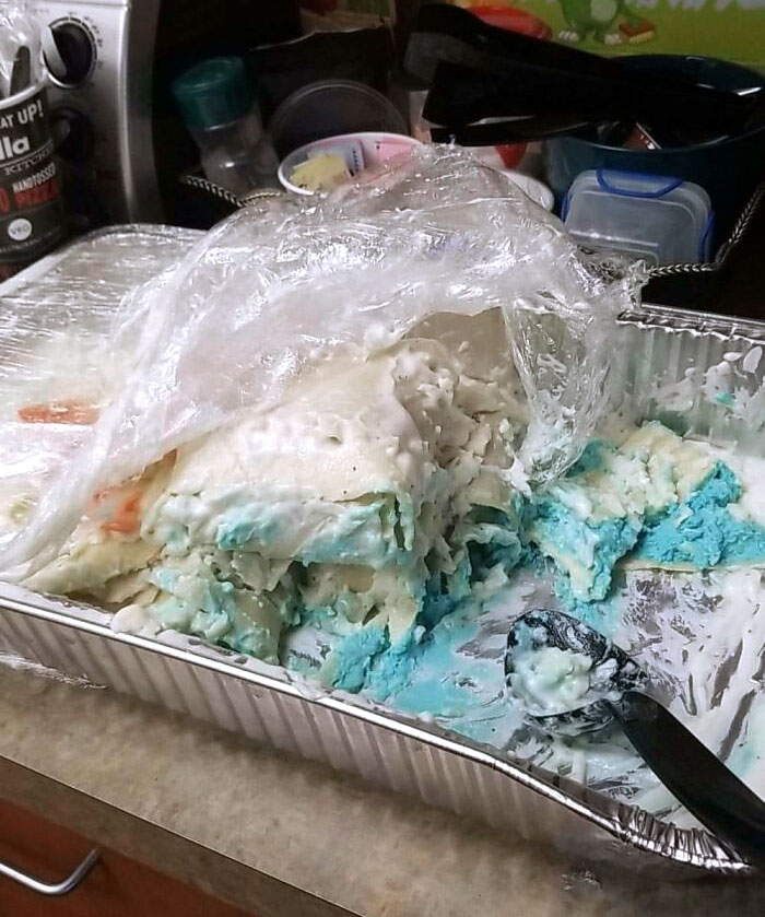 A gender reveal dessert in a pan, showing messy layers of white and blue filling, indicating a baby boy.
