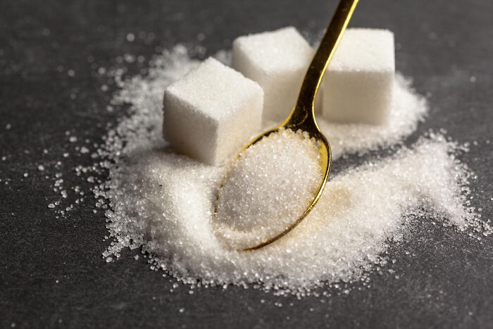 A golden spoon with sugar and sugar cubes, symbolizing common things that are far worse than we realize.