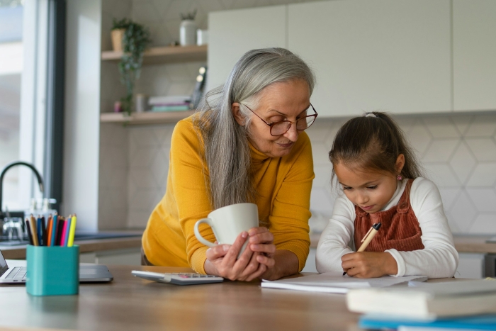 An older female nanny helps a young girl with her homework, showing support for the kids. An older female nanny helps a young girl with her homework, showing support for the kids.